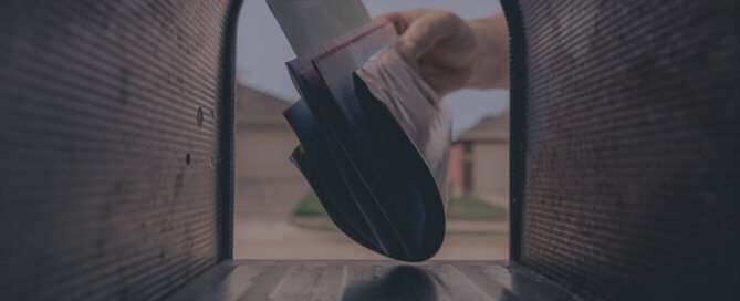 A person putting mail inside a mail box