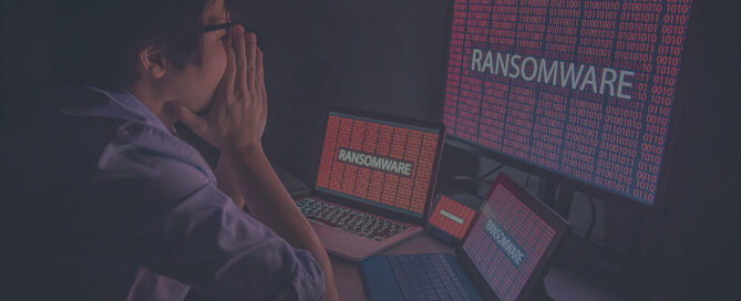 Asian man using three computer discovers finds ransomware.