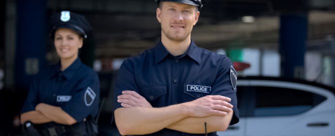 Two police officers standing in front of a police car.