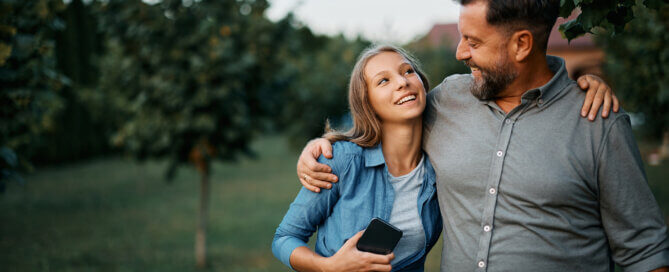 Embraced teenager girl and her father communicating in the backyard.