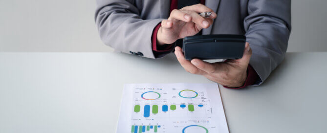 Close up view of businessman using a calculator to calculate financial accounts at his office desk.