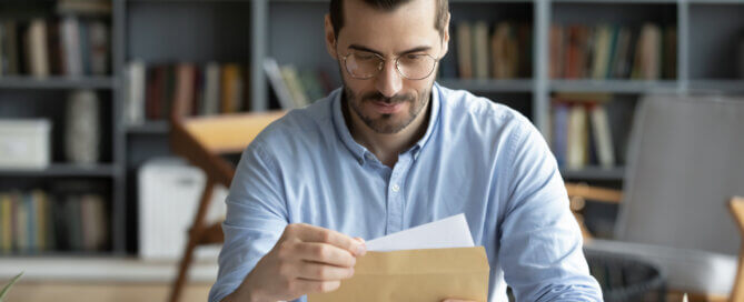 Man sitting at desk holding an envelope