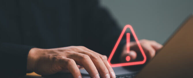 person using computer laptop with triangle caution warning sign for notification error